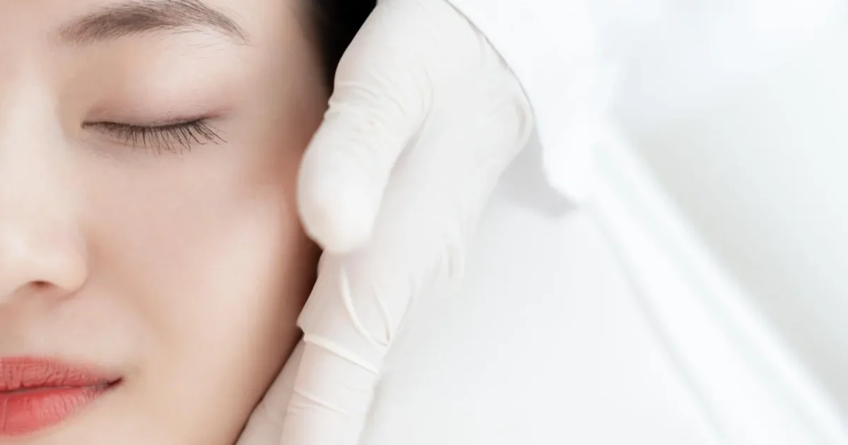 woman laying down with a gloved hand beside her face