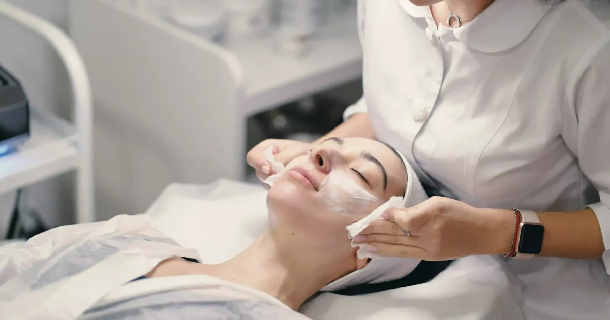 woman wiping cream on patient's skin