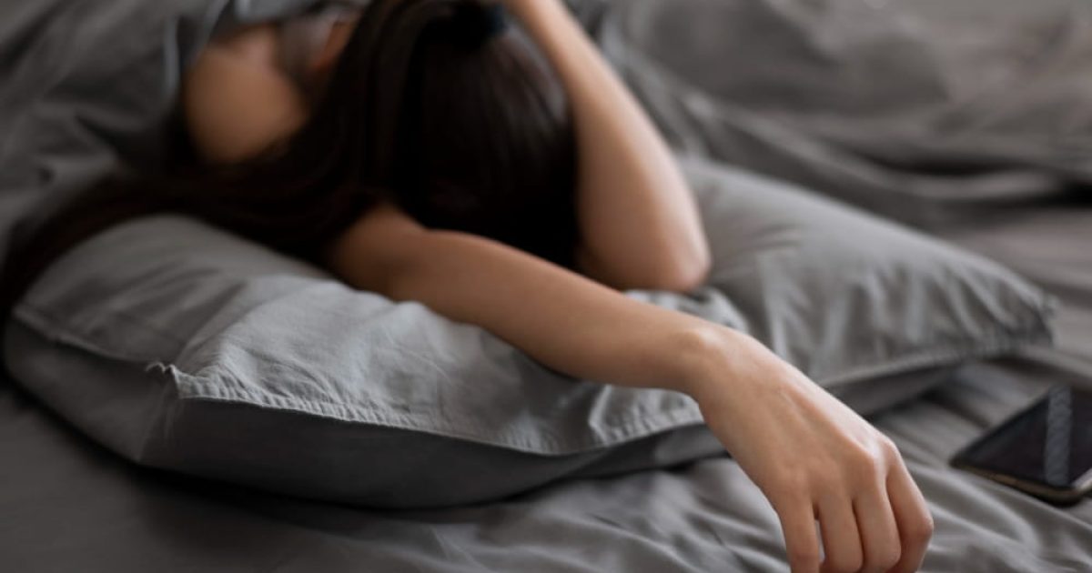 woman sleeping in bed with a hand on her head